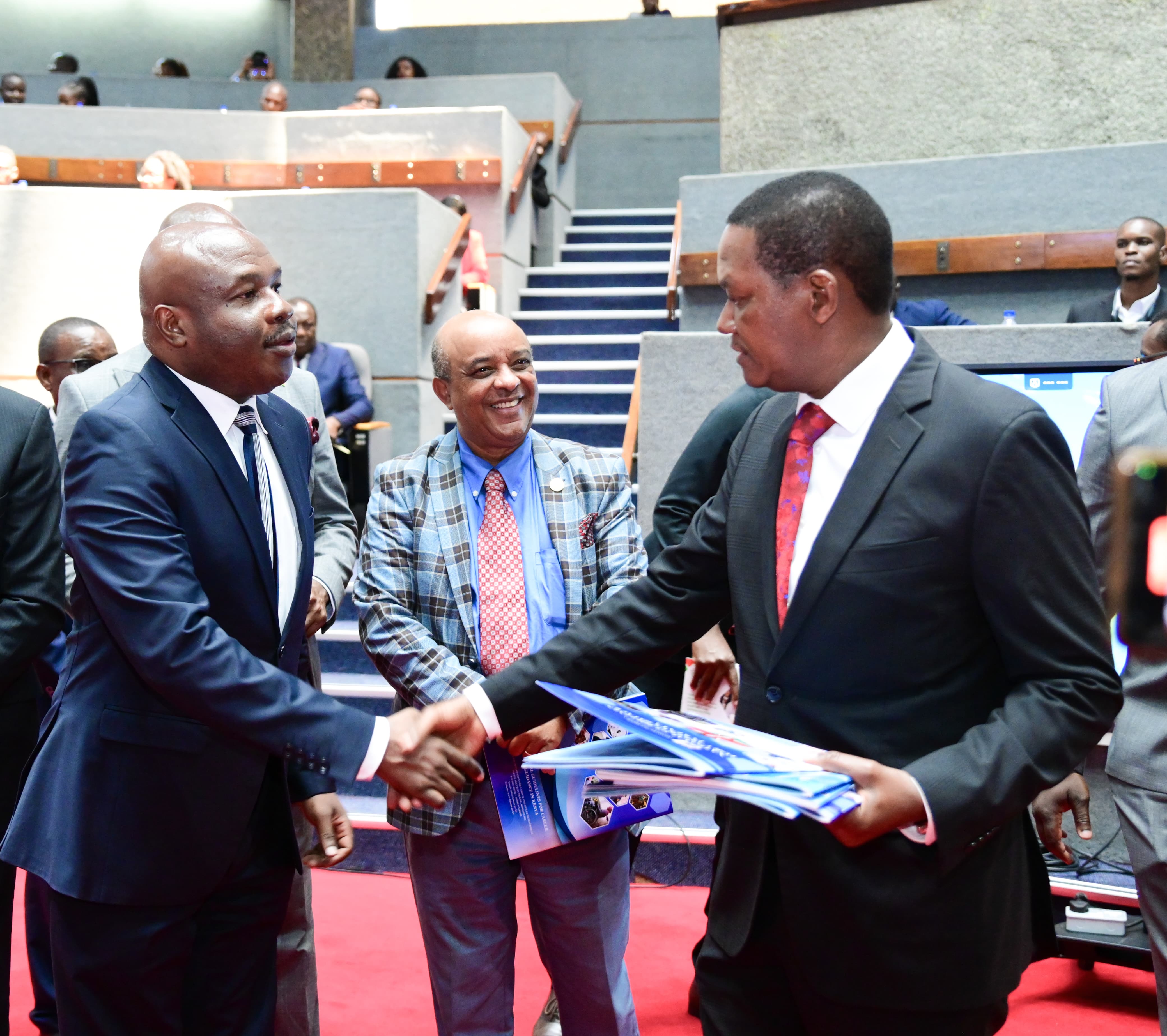 Labour Cabinet Secretary Dr. Alfred Mutua hands over policy framework documents to the Prinicipal Secretary State Department for Labour, Mr.Shadrack Mwadime (lefT) launched during the East African Employability summit. Looking on (centre) Dr.Meshesha Shewaraga,representing the African Union Commission