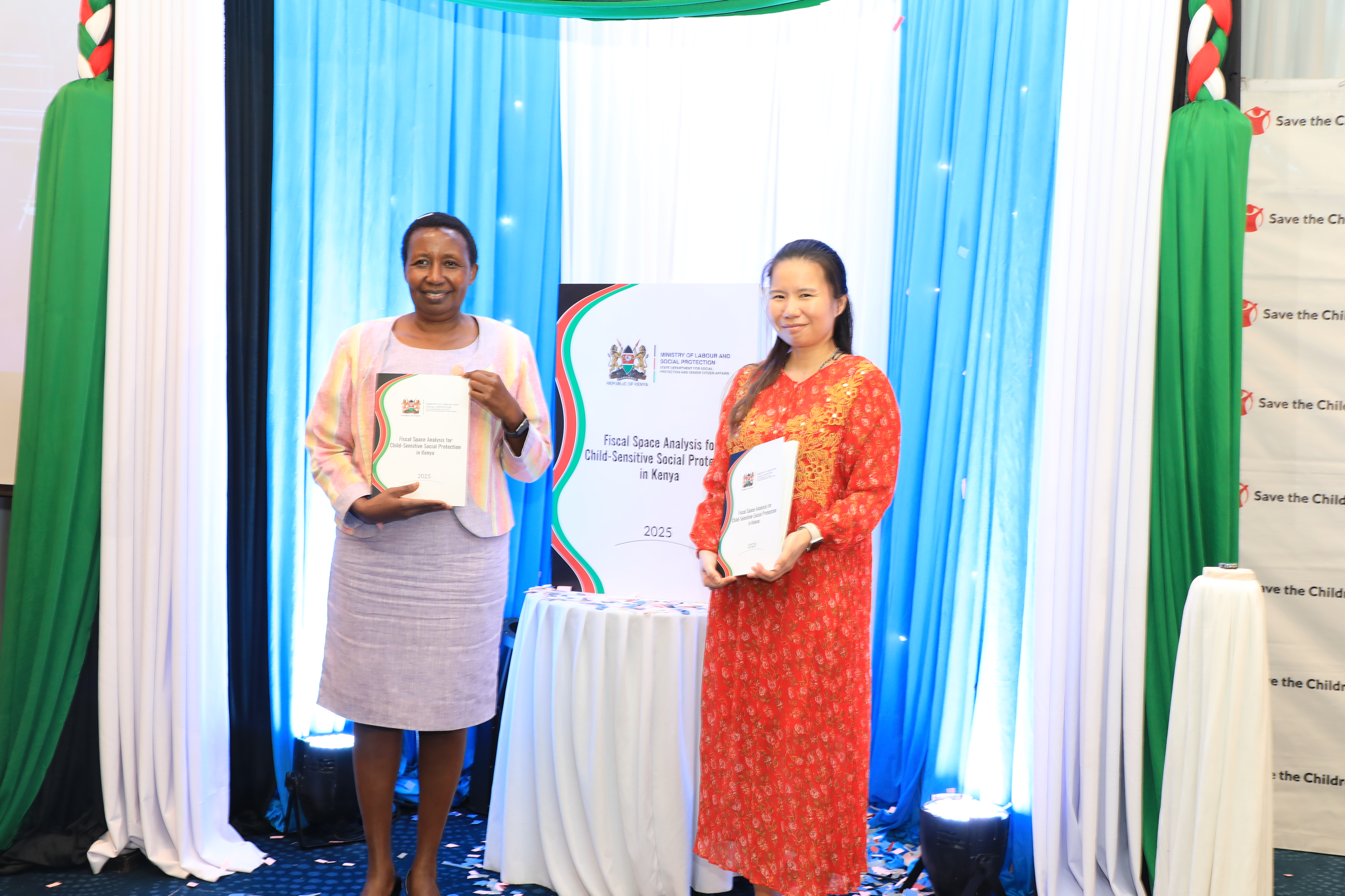The Director, National Social Protection Secretariat, Jane Kitili (left) poses with the Fiscal Space Analysis Report booklet alongside Country Director, Save the Children International, Pornpun Jib Rabiltossaporn, during the launch of the Fiscal Space Analysis Report on Universal Child Benefit (UCB), Programme at a Nairobi Hotel.