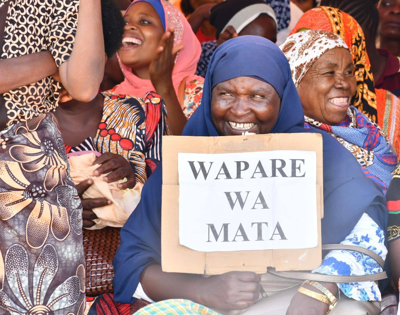 A woman smiles as she holds a placard in support of the new development that would see full recognition of the Pare community as part and parcel of Kenya.