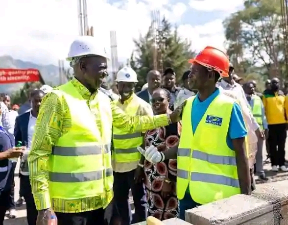 President William Ruto, left in white helmet, speaks to a construction worker, after laying a foundation block for a 50-bed capacity inpatient block at Meteitei Sub- county hospital in Tinderet Sub-county in Nandi. 