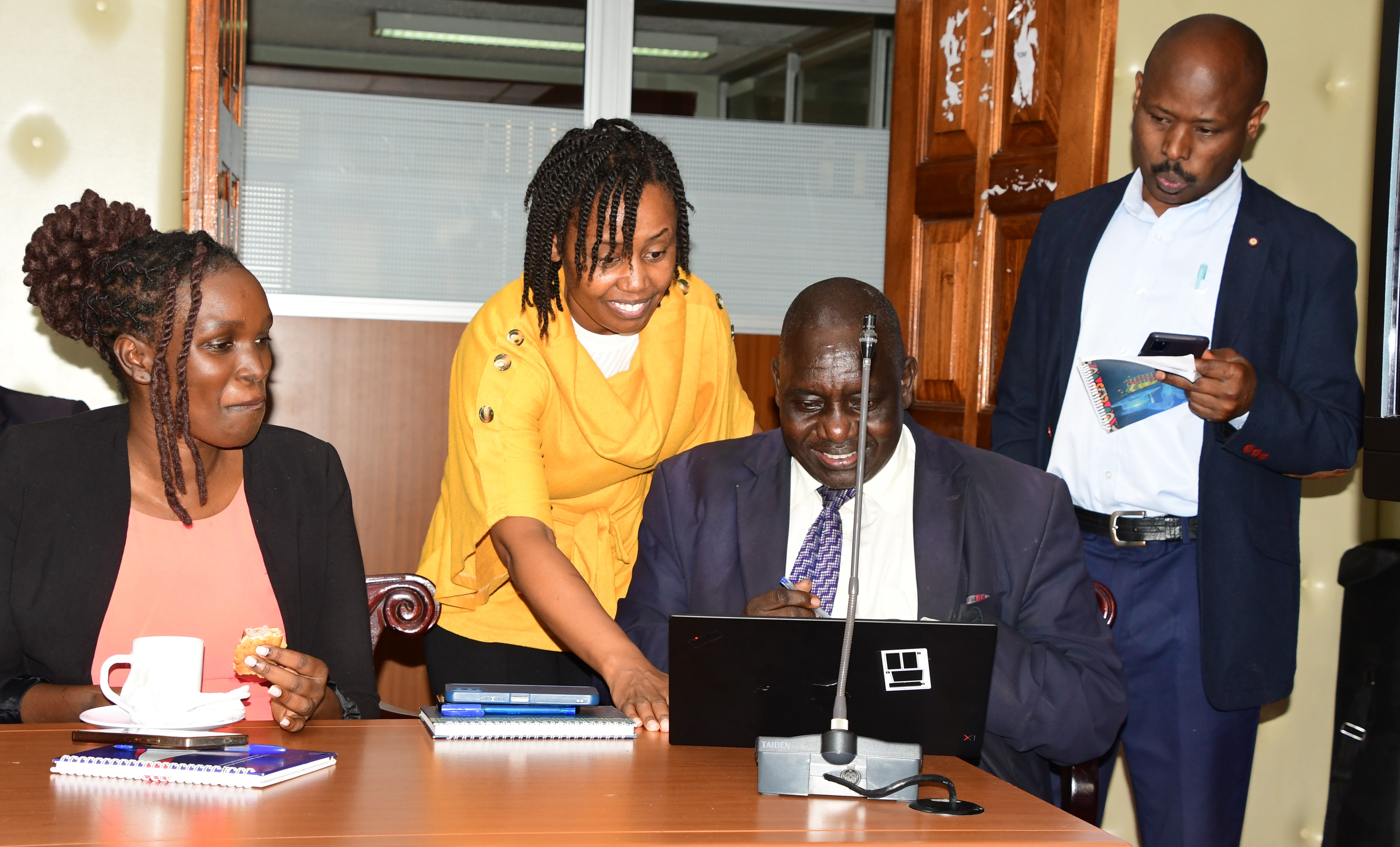 Postal Corporation strategic consultant Alice Gathoni demonstrating to the Director of Information, Joseph Kipkoech how to download the Postapay app at Teleposta Towers during the sensitization and demonstration meeting.