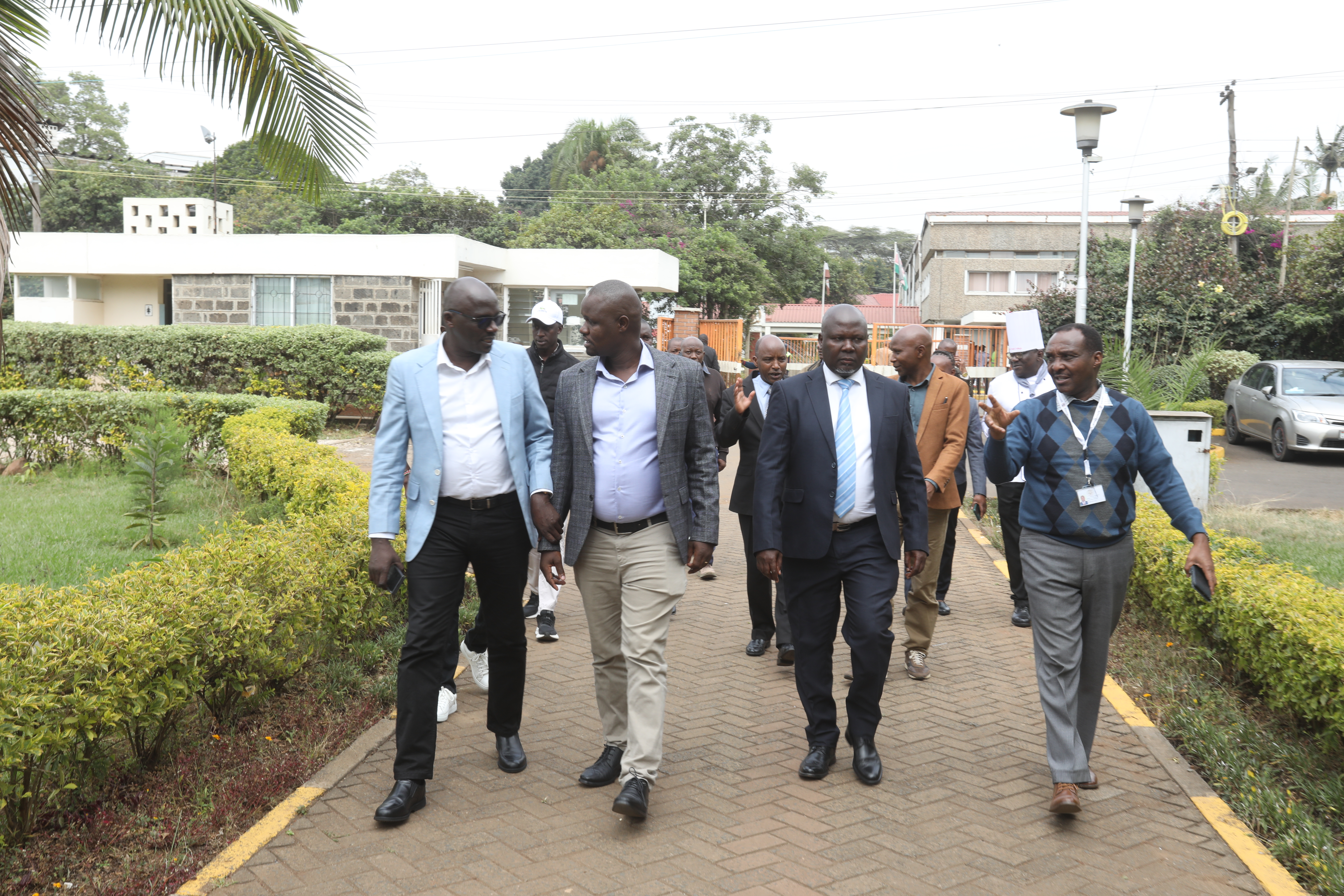 Dr Kanani and Mr Rachuonyo with county officials outside Kitui County Government headquarters.