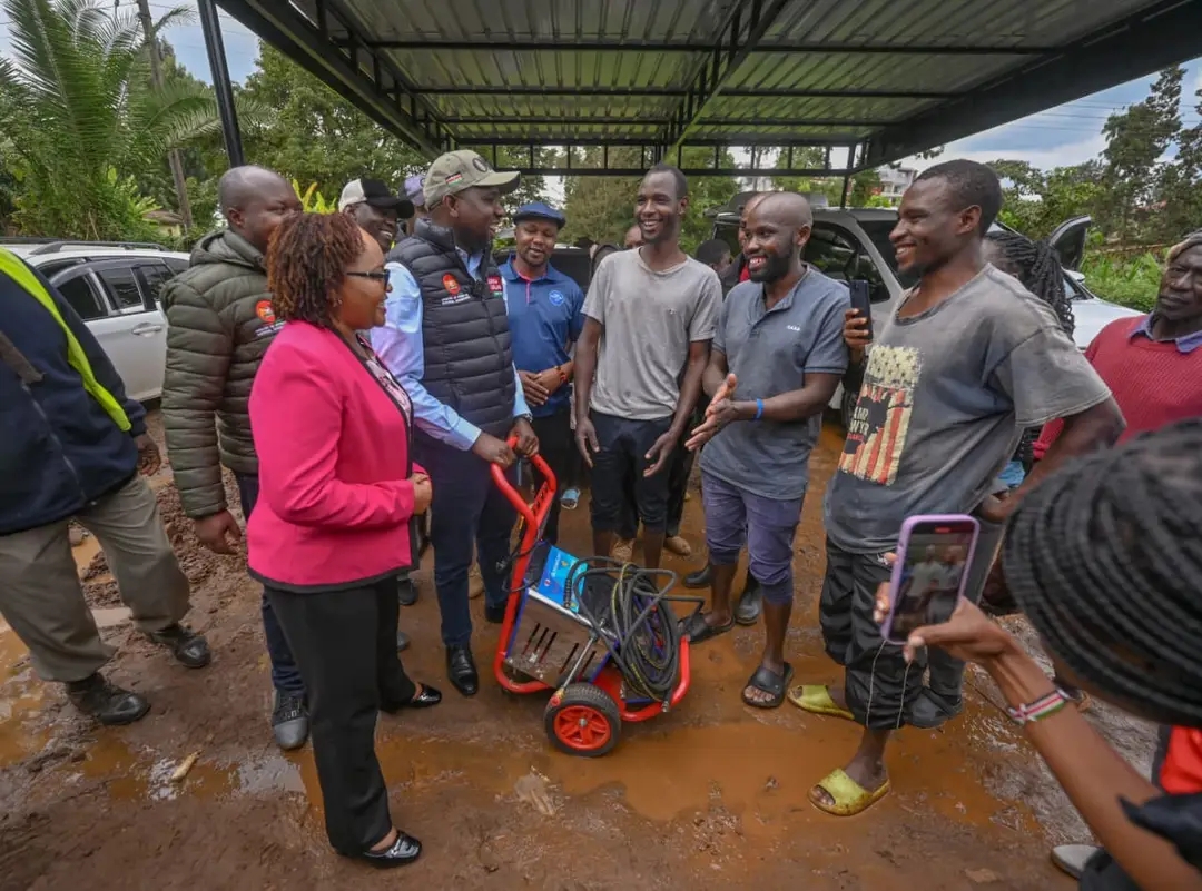 Interior CS Kipchumba Murkomen (in cap) hands over a modern carwash machine to members of Highway Jikuzee Carwash, Kerugoya, alongside Governor Anne Waiguru.