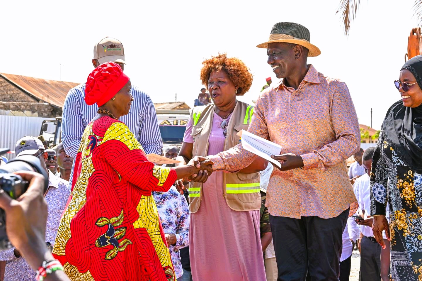 A Kwale resident receives a title deed from President  William Ruto. Looking on is Lands Cabinet Secretary Alice  Wahome. 