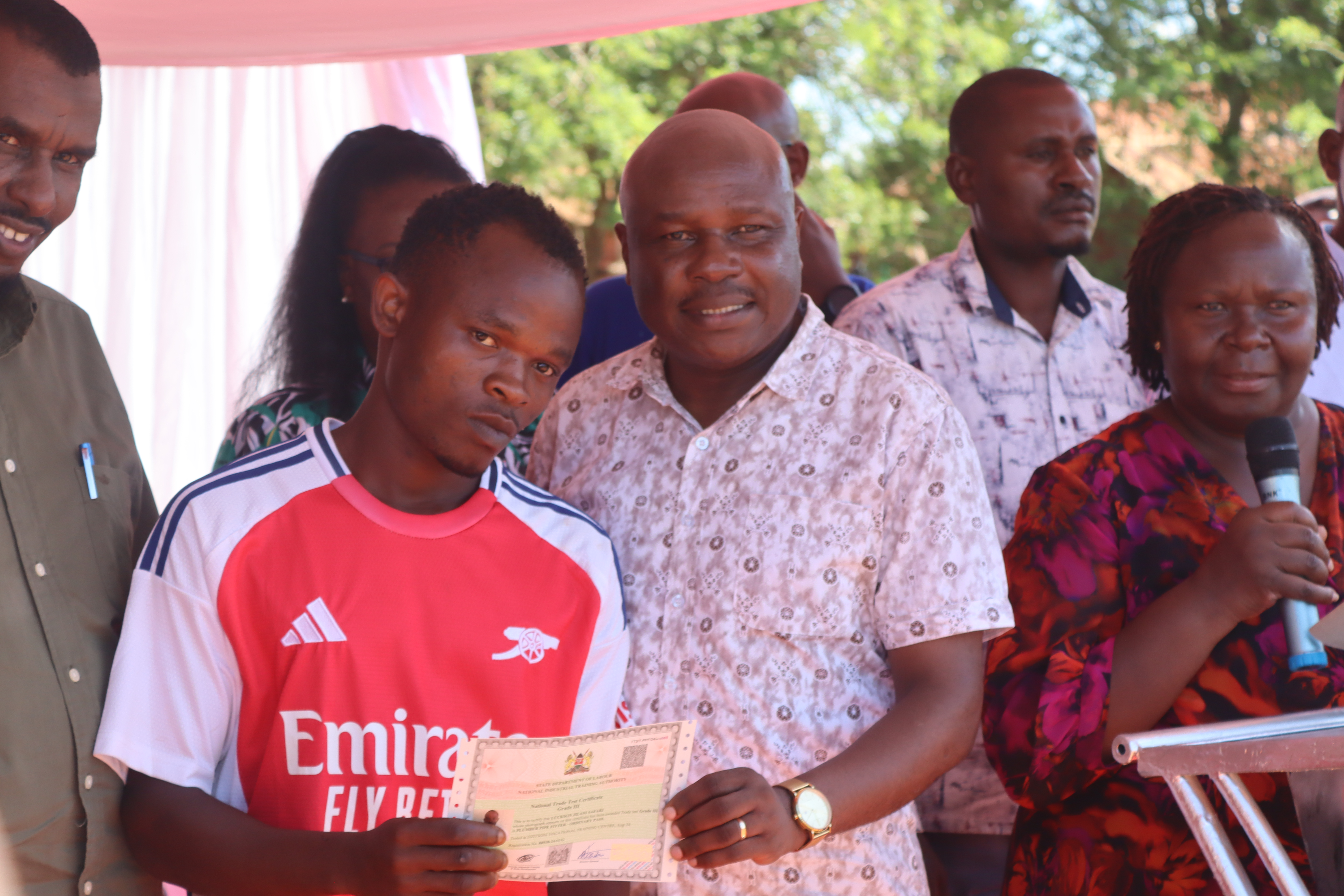 Shadrack Mwadime, Principal Secretary State Department for Labour and Skills Development handing over a Trade Test Certificate to one of the students at Dzitsoni Vocational Technical Training Center