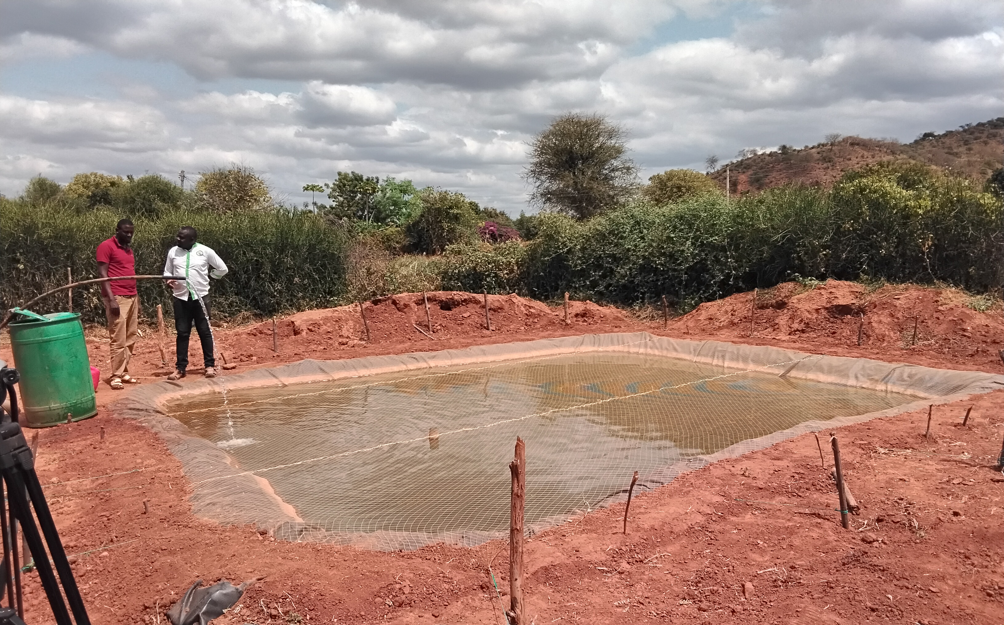 Marsabit county Fisheries Officer Sostine Wanjala (in white shirt) offering technical advice about fish meal ratio to a youthful fish farmer, Musa Dida, from Odda ward, Moyale sub county. 