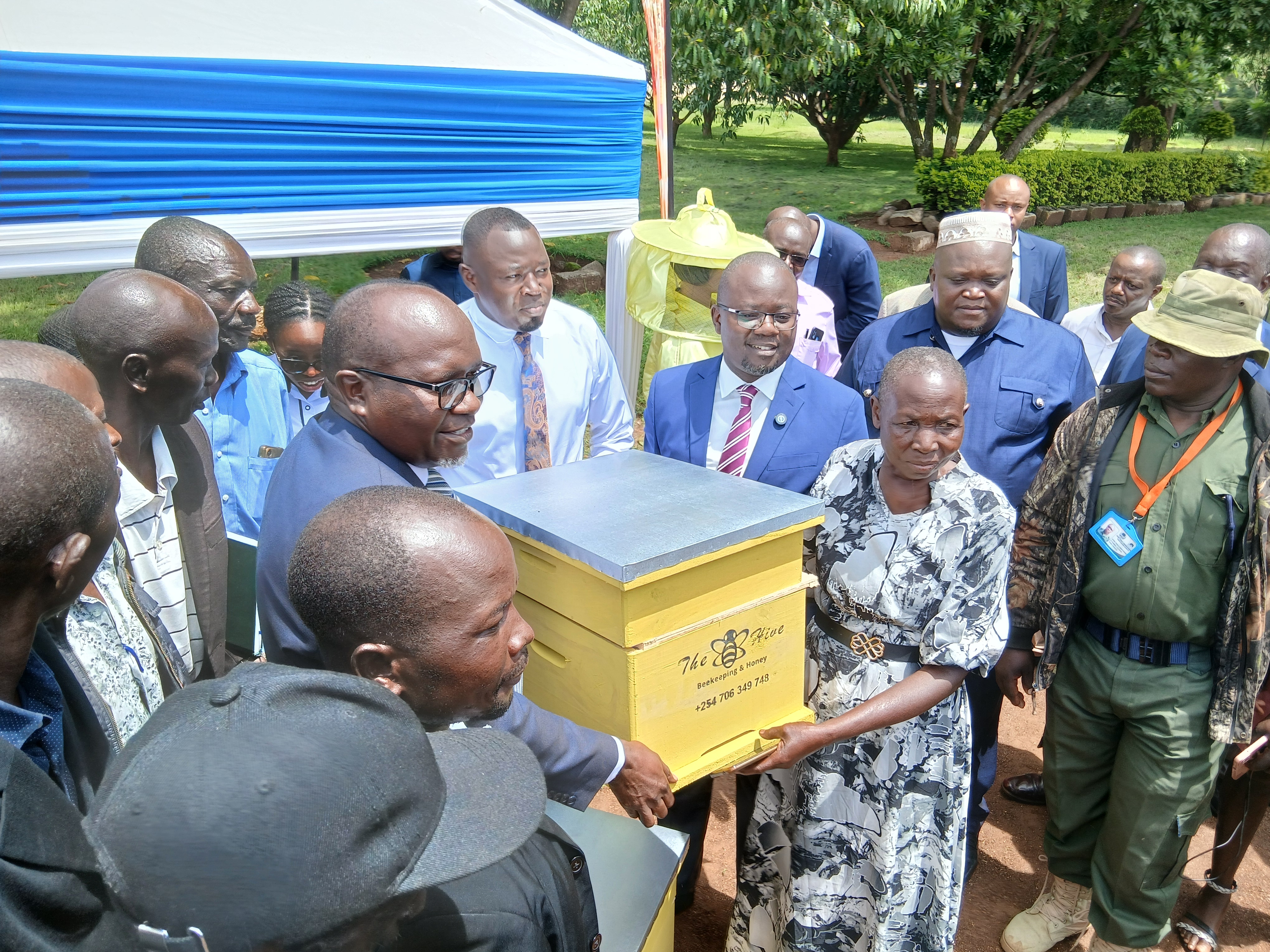 LBDA MD Wycliffe Ochiaga (in blue suit) presents a beehive to one of the beneficiaries during the launch of the project in Kisumu