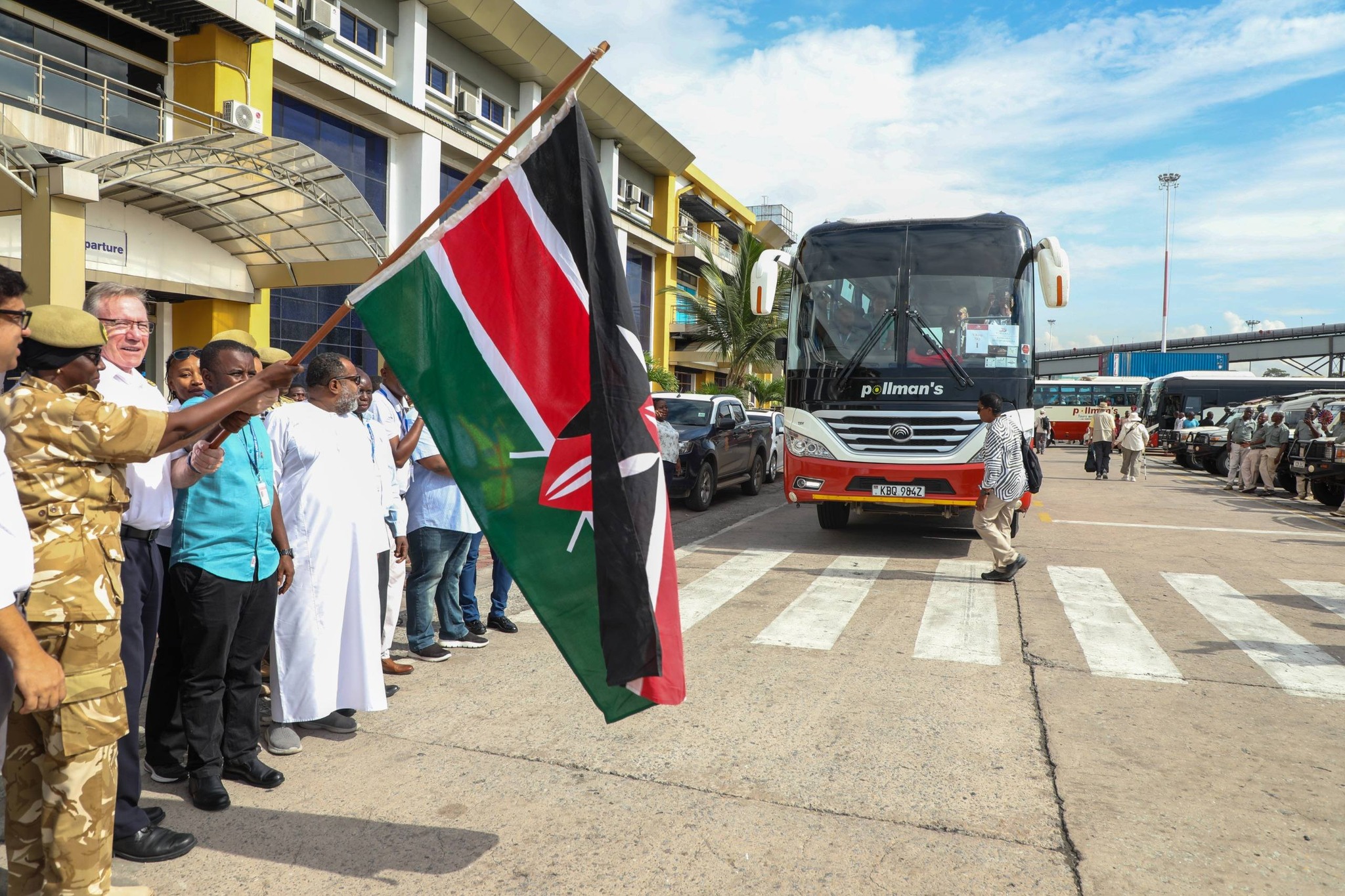 KWS Senior Assistant Director for the Coast Conservation Area, Elema Hapicha, and Viking Sky Captain Gerry Hogan (centre, in white) flag off tourists outside the Arrival Terminal at the Port of Mombasa on Thursday, as KWS officers line up alongside safari vehicles bound for various wildlife and cultural destinations across Kenya
