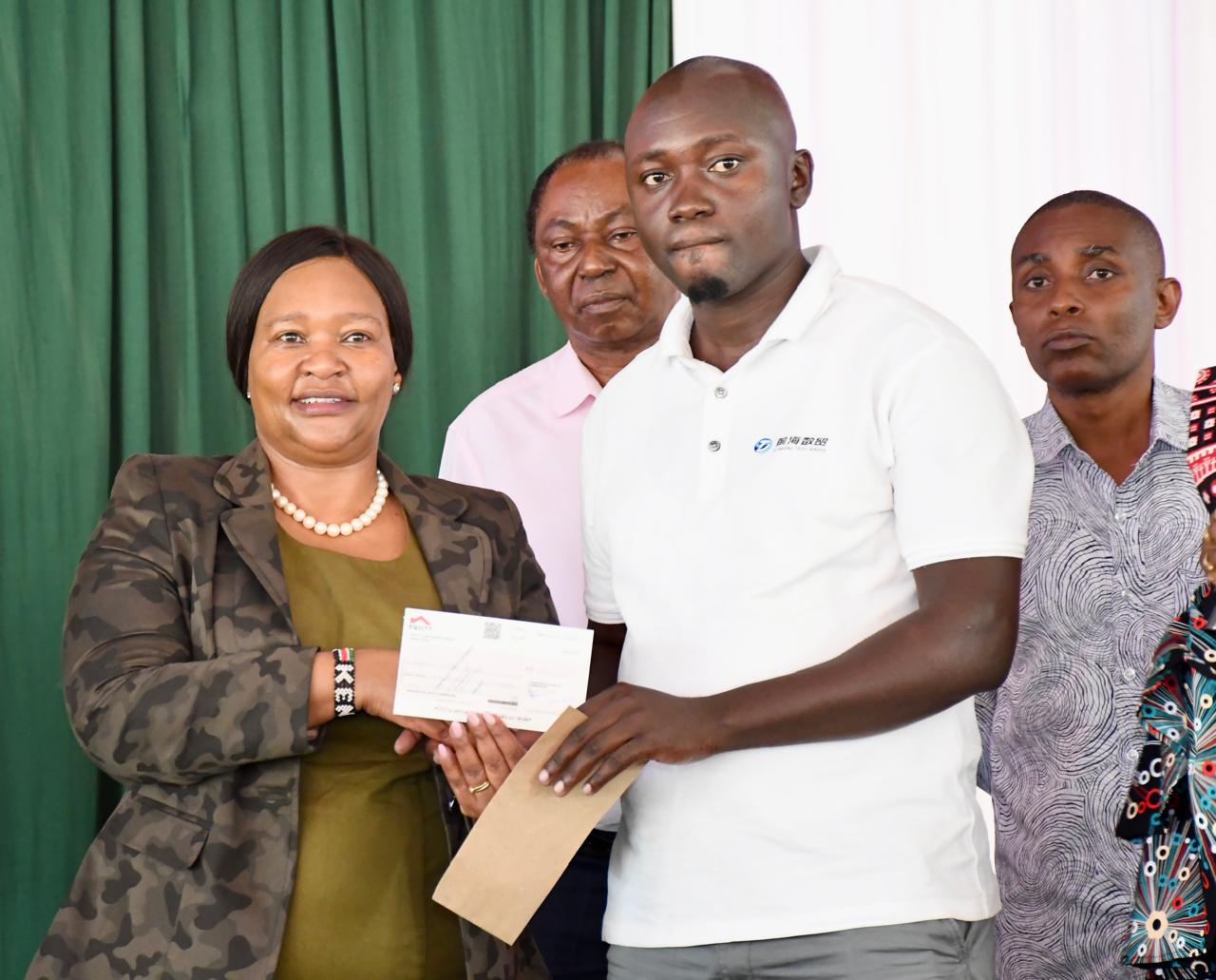 Tourism and Wildlife Cabinet Secretary, Rebecca Miano, hands over a cheque to a relative of a victim of human-wildlife conflicts at the Marafa Vocational Training Centre in Magarini Sub County.