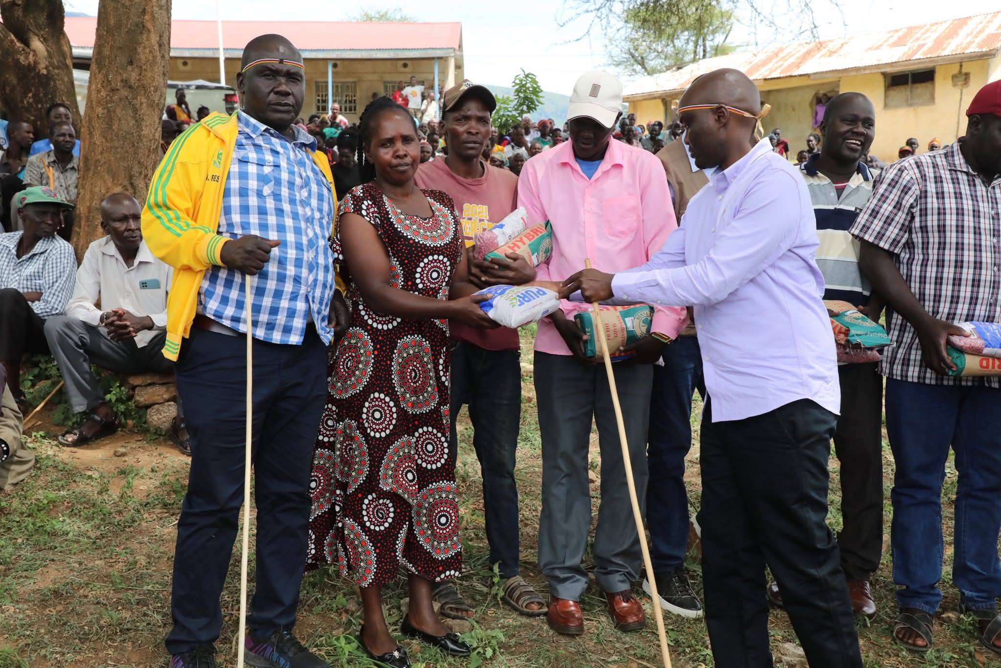 Elgeyo Marakwet Governor Wisley Rotich, (right), handing over packets of seeds to residents of Endo Ward, Kerio Valley Sub-County