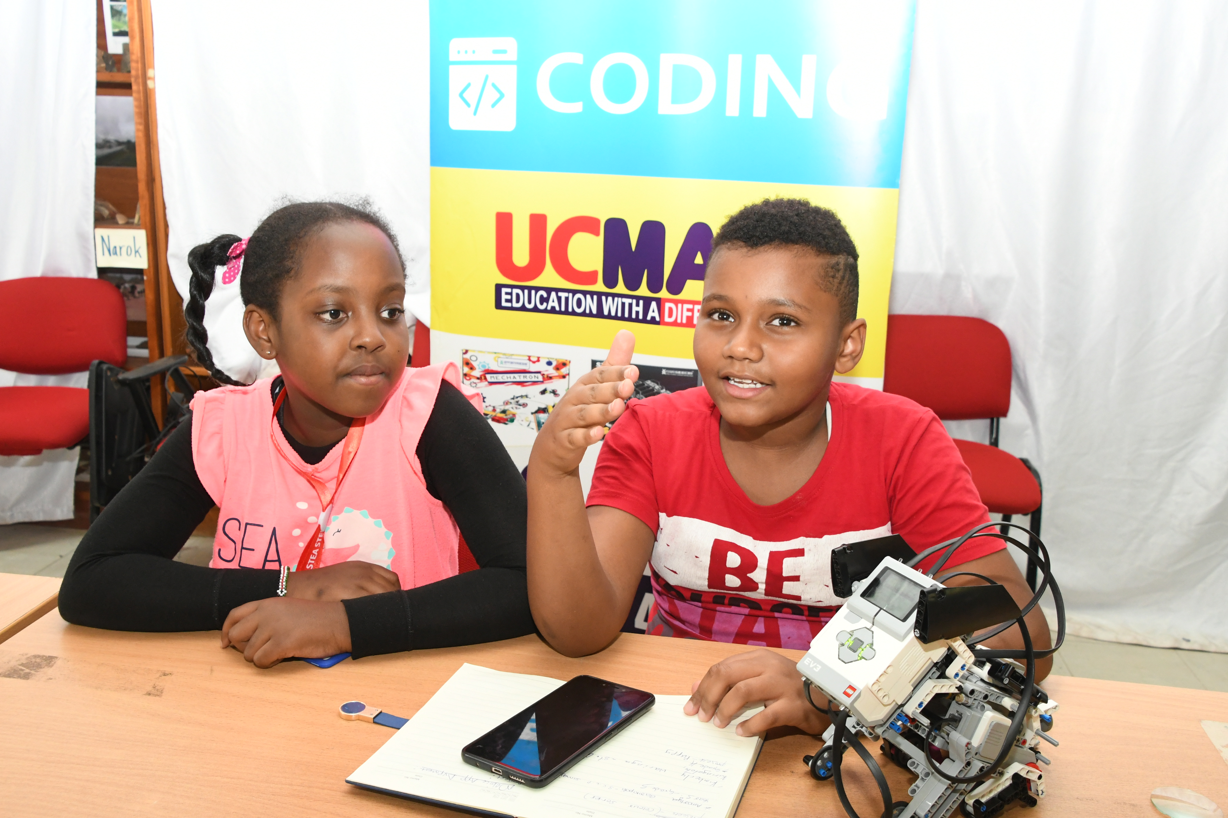 Giovanni Kei (R), who is a grade five student at St. Hannah's Nairobi and a grade four pupil at St. George Kiringatah, Nairobi, Kimberly Waringa, demonstrating how a smart puppy. Photo/Bonface Malinda