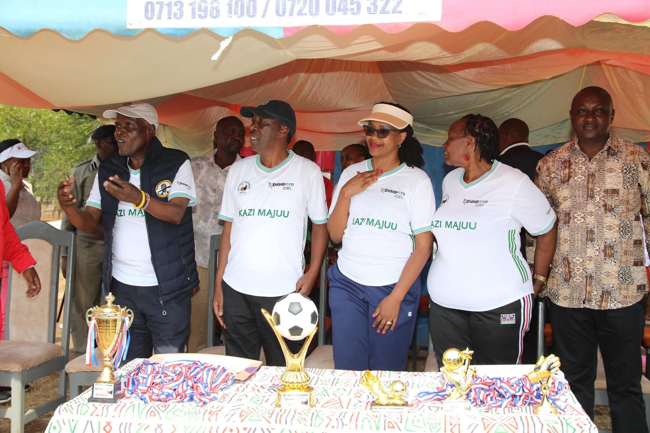 Diaspora Affairs Roseline Njogu poses for a photo with players during the launch of the Kazi Majuu football tournament.