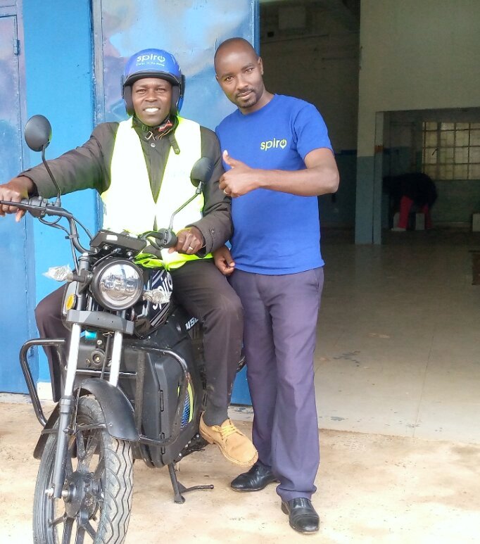 A satisfied boda boda operator Bernard Tonui poses with his newly acquired electric bike at the Spiro Kericho branch. On the right is a sales agent with Spiro Company, Aaron Koech. PHOTO: SARAH NJAGI