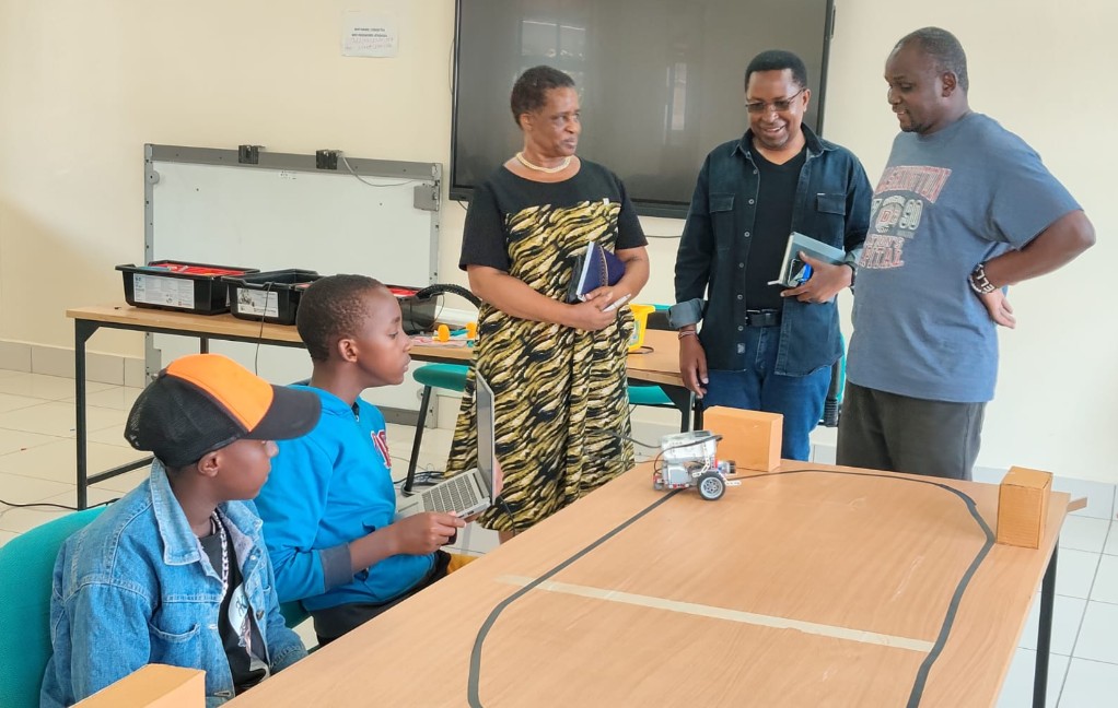 The Acting Chief Executive Officer of CEMASTEA, Gladys Masai (left standing), assesses a PID colour sensor project alongside National Trainer and Coordinator of the STEM Boot Camp at CEMASTEA, Mr. Martin Mungai (centre standing), and a STEM trainer (right), as learners showcase innovative solutions developed during a five-day STEM Boot Camp.
