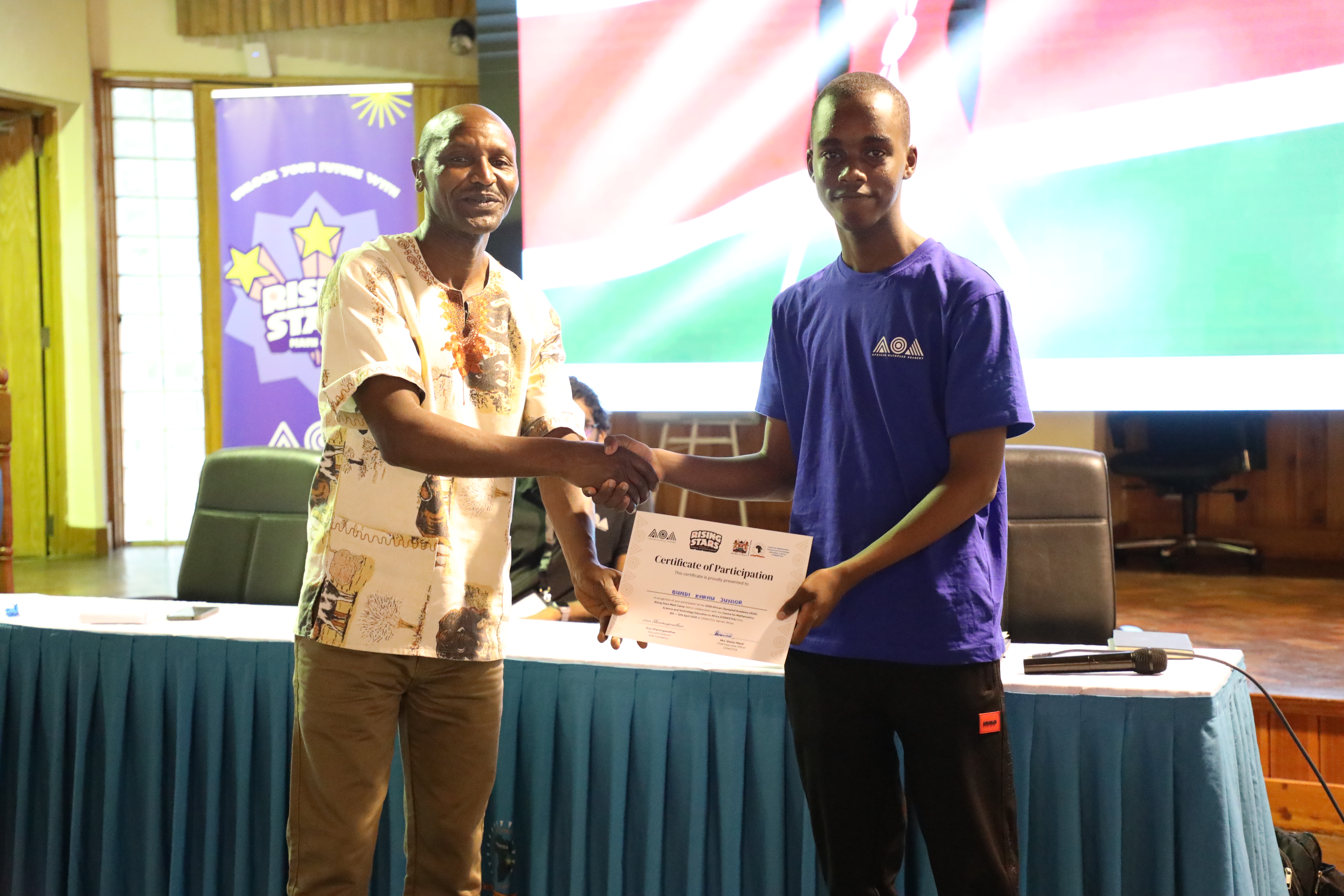 Co-founder and Executive Director of the African Olympiad Academy, Arun Shanmuganathan (R), presents a certificate to one of the students during the closing ceremony of the 2026 African Olympiad Academy (AOA) Rising Stars Training Camp at Karen Campus, Nairobi