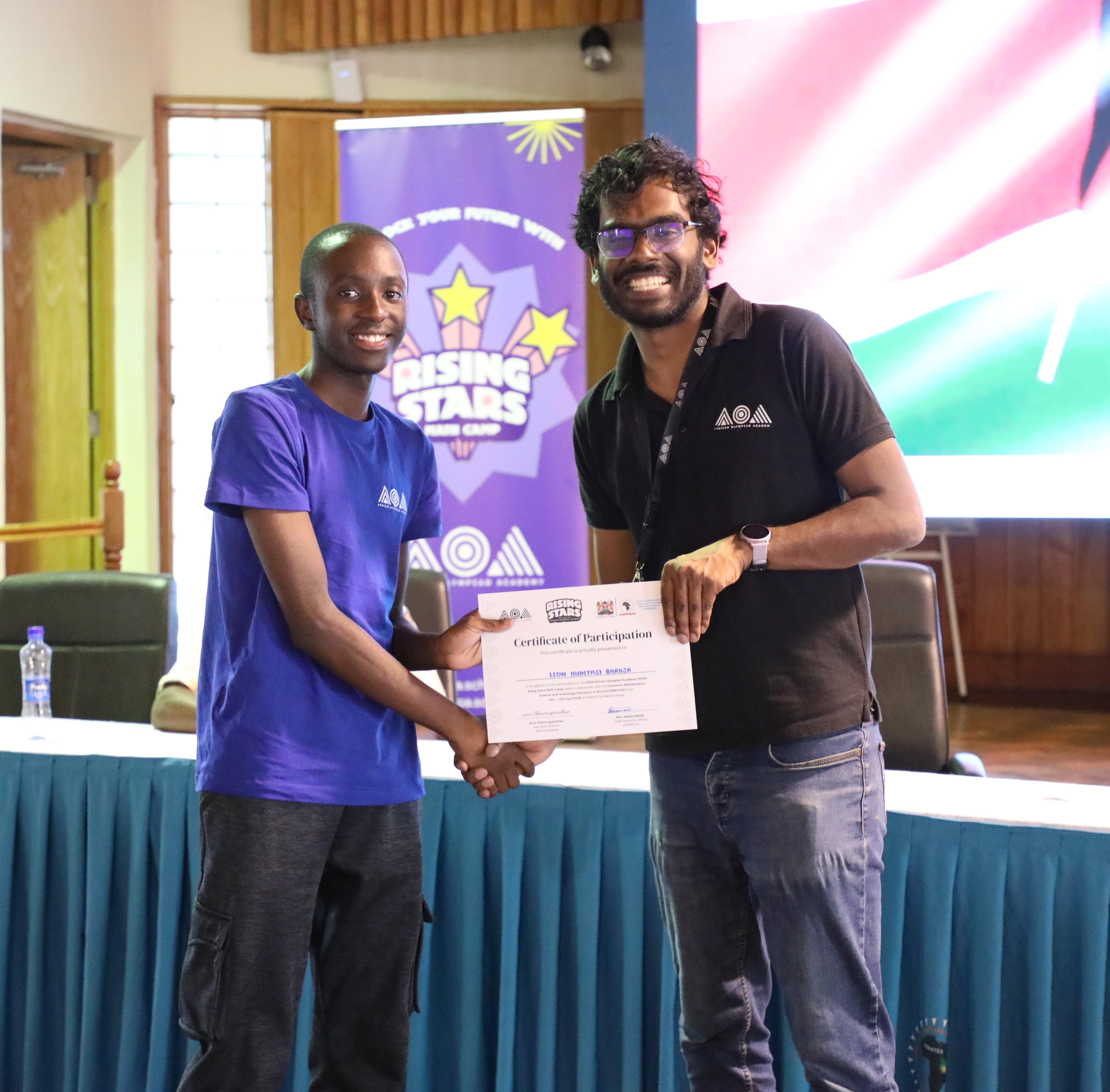 Acting Director of STEM Research and Innovation, Karanja Mutito (L), presents a certificate to one of the students at Karen Campus, Nairobi,