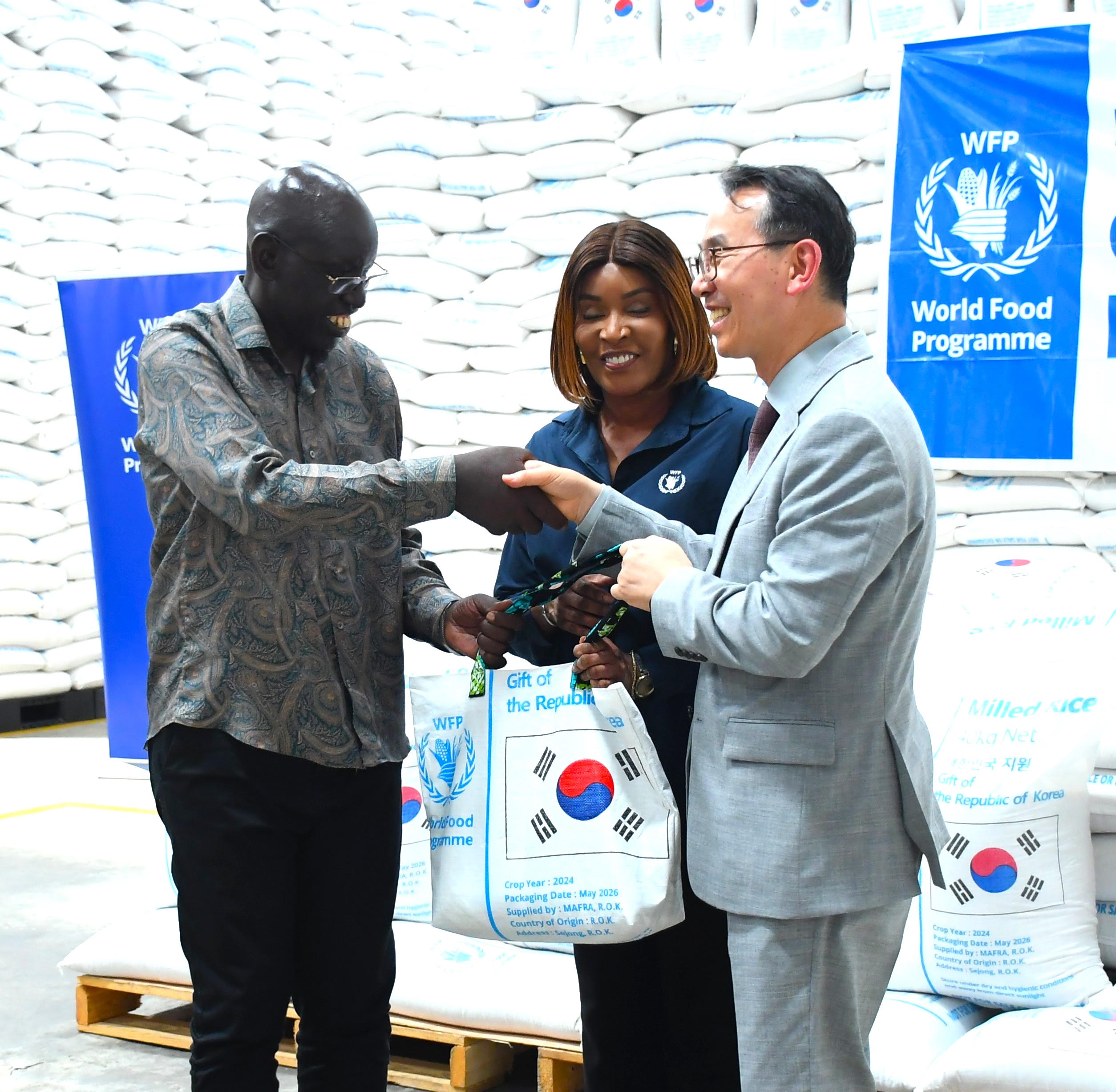 The Principal Secretary for Immigration and Citizen Services, Dr Belio Kipsang (left), receives a symbolic bag of rice from Ambassador of the Republic of Korea to Kenya, Kang Hyung-shik (R), as WFP Country Director, Ms Betty Ka (C) looks on, during the Korea-WFP rice handover ceremony held at the WFP offices, Mombasa.