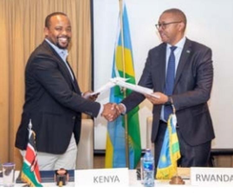 Lands PS Generali Nixon Korir (Left) and the Head  of the Rwandan delegation First Counsellor Donne  Besigye exchange copies of the report during a meeting in Nairobi.