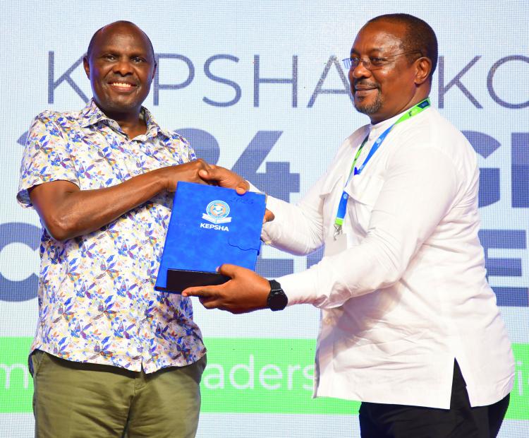 Chief of Staff and Head of Public Service Felix Koskei (L) receives memorabilia from chairperson of the Kenya Primary School Heads Association (KEPSHA) chairperson Johnson Nzioka during the opening session of the 25th annual general meeting and conference, Mombasa