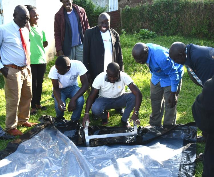 odgers Alinda from Sky Bold (white T-shirt) shows beneficiary CBO representatives how to fix a bubble-dryer at the Agriculture offices in Lumakanda