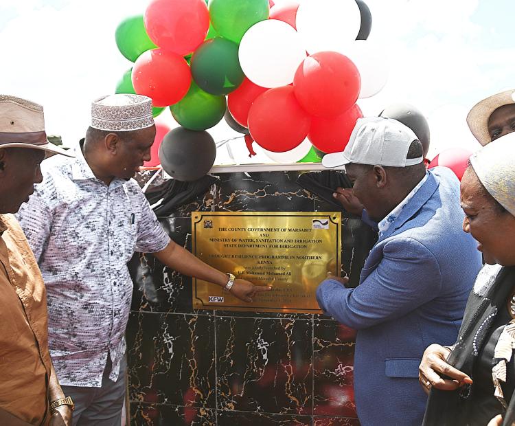 The principal secretary for irrigation CPA Ephantus Kimotho (grey coat) and Marsabit governor Mohamud Ali unvail the plaque during the launch of the Drought Resilience Programme in Northern Kenya (DRPNK) at Bambala-Fachana in Sololo Sub-County.