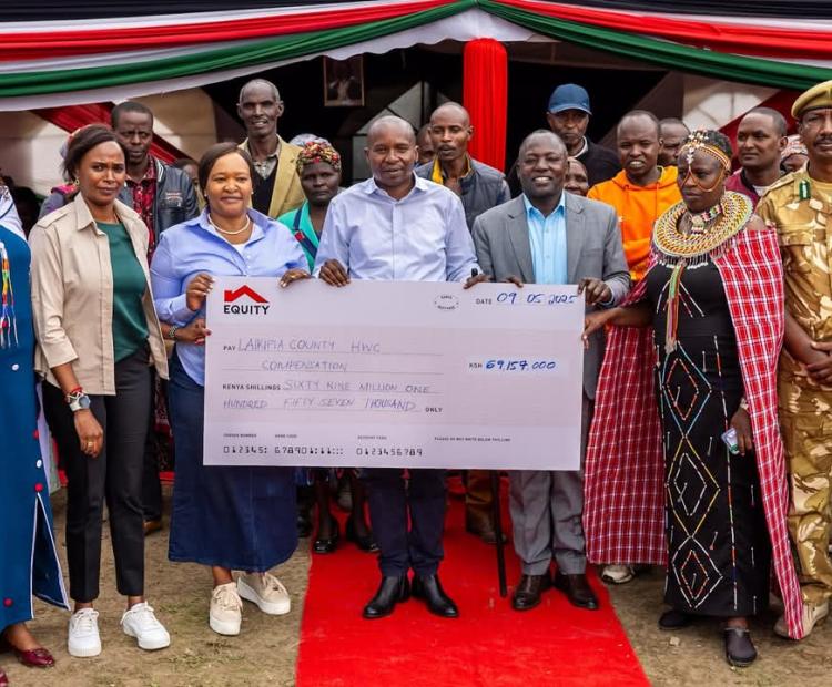 Deputy President Prof. Kithure Kindiki (centre in white shirt) accompanied by CS Tourism and Wildlife Rebecca Miano (L), and Laikipia Governor Joshua Irungu display a dummy cheque for victims of human-wildlife compensation at Naibor centre