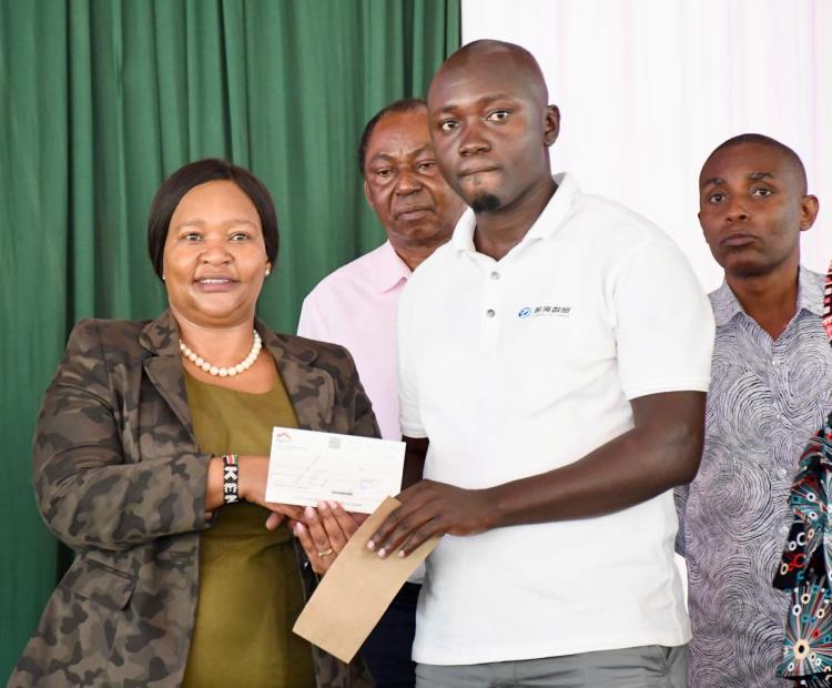 Tourism and Wildlife Cabinet Secretary, Rebecca Miano, hands over a cheque to a relative of a victim of human-wildlife conflicts at the Marafa Vocational Training Centre in Magarini Sub County.