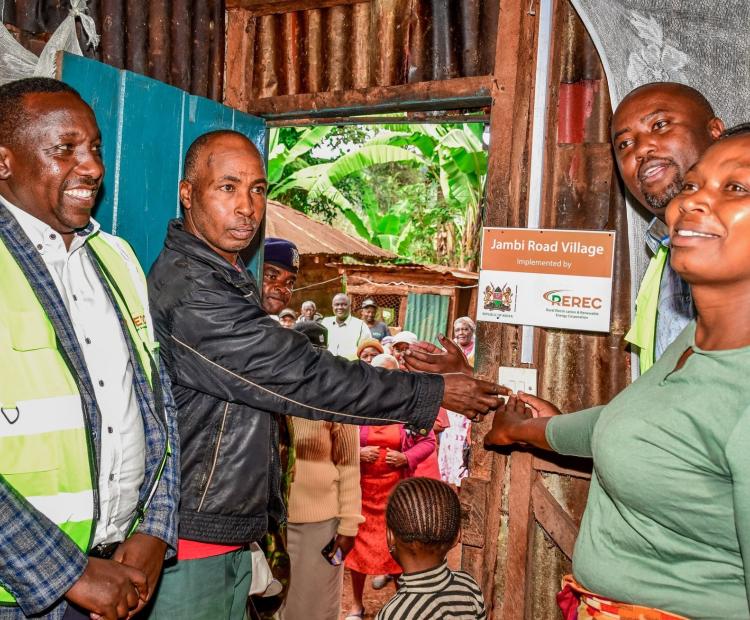 Principal Secretary for Energy Alex Wachira helps a family to switch on light. The household is one of the beneficiaries of power connection in Kangema constituency.
