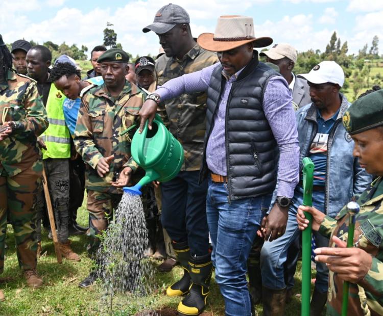 The Principal Secretary for State Department for Environment and Climate Change, Dr. Eng. Festus Ng’eno (centre) waters a tree during a planting exercise in Kuresoi, Nakuru County.