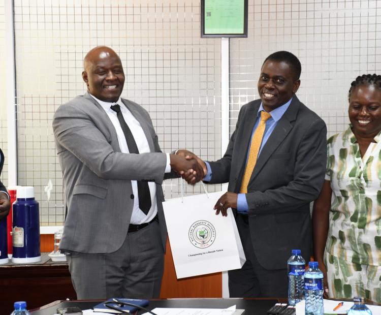 Mr. Josphat Muchiri, Director Technical Services(left)  at National Biosafety Authority presents a gift to  Prof. Prof. Danston Lilechi,  acting Deputy Vice -Chancellor for Planning, Research and Innovation, at asinde Muliro University of Science and Technology. The two leaders agreed o come up a memorandum of understanding (MoU) by end of March.
