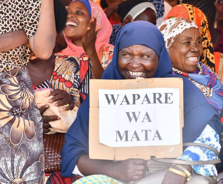 A woman smiles as she holds a placard in support of the new development that would see full recognition of the Pare community as part and parcel of Kenya.