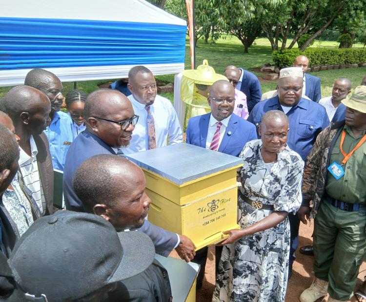 LBDA MD Wycliffe Ochiaga (in blue suit) presents a beehive to one of the beneficiaries during the launch of the project in Kisumu