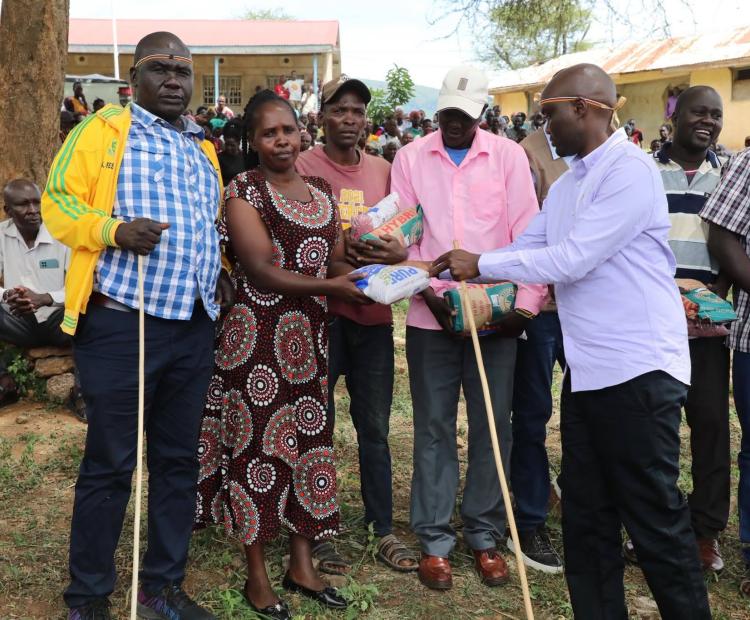 Elgeyo Marakwet Governor Wisley Rotich, (right), handing over packets of seeds to residents of Endo Ward, Kerio Valley Sub-County