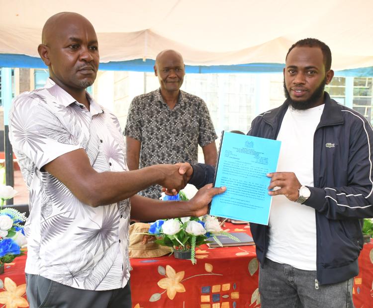 The Chairman Kiruki Kiende Farmers Cooperative Society, Bonface Kinyua Njiru (left), hands over the project contract documents for Kiruki Kiende irrigation project to Abubakar Mohamed from Gamachu Construction Limited (Contractor) as Director Irrigation Water Management,State Department for Irrigation, Daniel Odero looks on during the official site handover meeting at Kiruki Kiende Irrigation Water Users Association (IUWA) Offices in Gaturi South, Embu West Sub-County, Embu County.