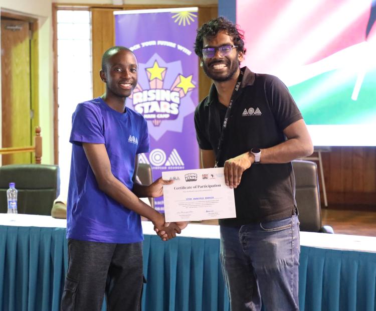 Acting Director of STEM Research and Innovation, Karanja Mutito (L), presents a certificate to one of the students at Karen Campus, Nairobi,.