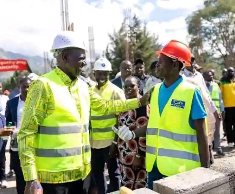 President William Ruto, left in white helmet, speaks to a construction worker, after laying a foundation block for a 50-bed capacity inpatient block at Meteitei Sub- county hospital in Tinderet Sub-county in Nandi. 